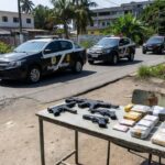 Viaturas policiais e armas e drogas apreendidas em operação contra quadrilha