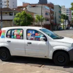 Carro com adesivos eleitorais para eleições 2026 em rua brasileira, aviso para seguradora