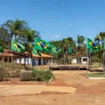 Praça pública em Colorado do Oeste com bandeiras do Brasil durante lançamento de candidaturas políticas